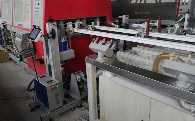 Window-profile extrusion line: the red machine and the laser marker column at the profile outlet